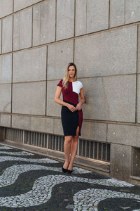 Portrait of woman standing against building