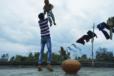 People playing with ball in water against sky