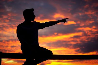 Silhouette man standing against orange sky