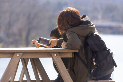 Rear view of woman sitting on pier