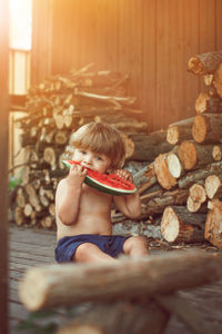 Portrait of cute boy eating watermelon sitting outdoors