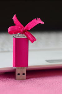 Close-up of usb stick with pink ribbon in laptop