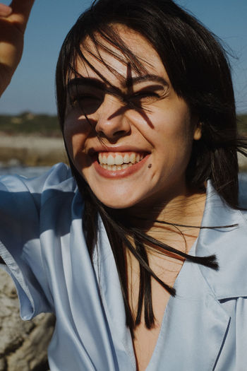 CLOSE-UP PORTRAIT OF SMILING YOUNG WOMAN OUTDOORS