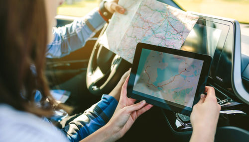 Young couple reading map on digital tablet in car