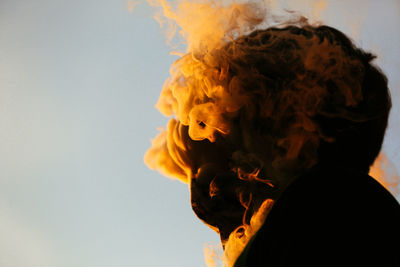 Portrait of young man smoking against sky