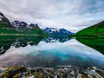 Scenic view of lake by snowcapped mountains against sky