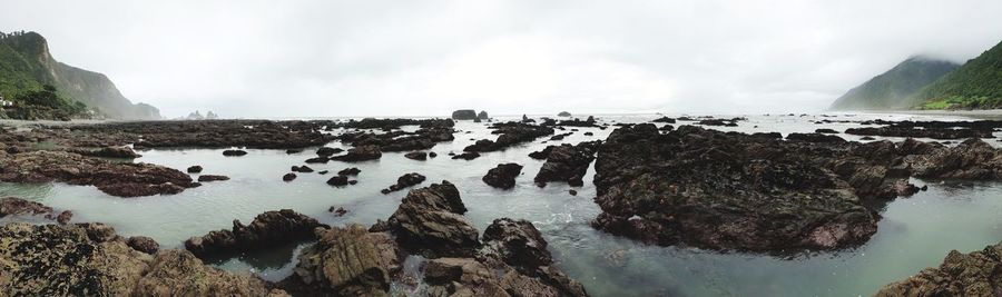 Panoramic shot of rocks in sea against sky