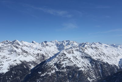 Scenic view of snowcapped mountains against blue sky