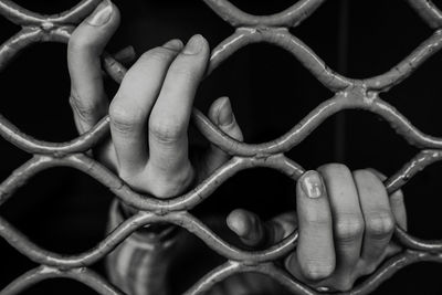 Cropped hand of woman holding metal grate in darkroom