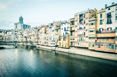 Buildings by canal against sky in city