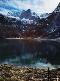 Scenic view of lake by snowcapped mountains against sky