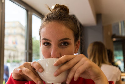 Portrait of young woman drinking coffee at cafe