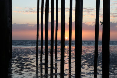 Scenic view of sea against sky through a wooden structure during sunset