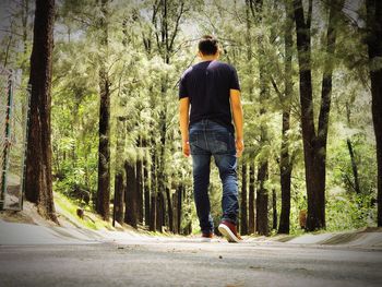Rear view of man walking on road in forest