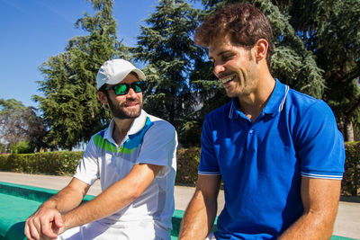 Tennis players sitting on steps against sky