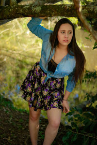 Woman looking away while standing against tree