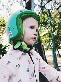 Cute girl wearing crash helmet against trees