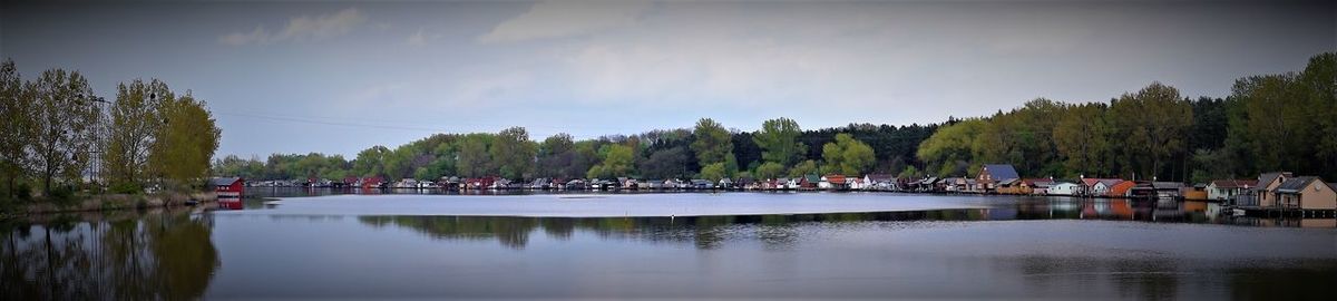 Panoramic view of crowd by river against sky