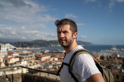 Portrait of young man standing against cityscape