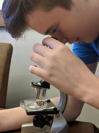 Close-up of boy looking through microscope