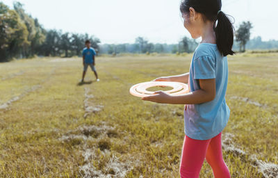 Siblings playing with plastic disc on field