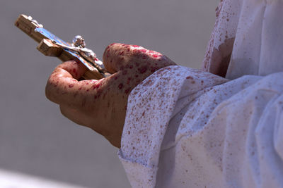 Midsection of man holding cross