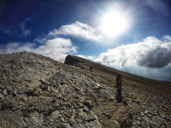 People climbing on mountain against bright sun