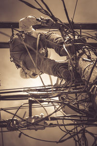 Low angle view of man standing on electricity pole