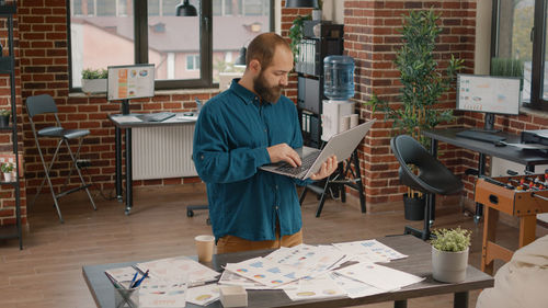 Portrait of man using digital tablet while sitting on table