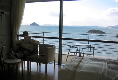 Man sitting on table by sea against sky