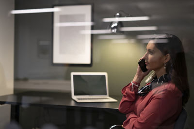 Businesswoman talking via phone in office