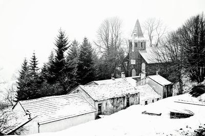 Snow covered trees and buildings against sky