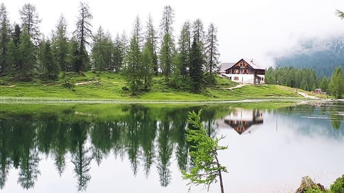 Reflection of trees and houses in lake against sky