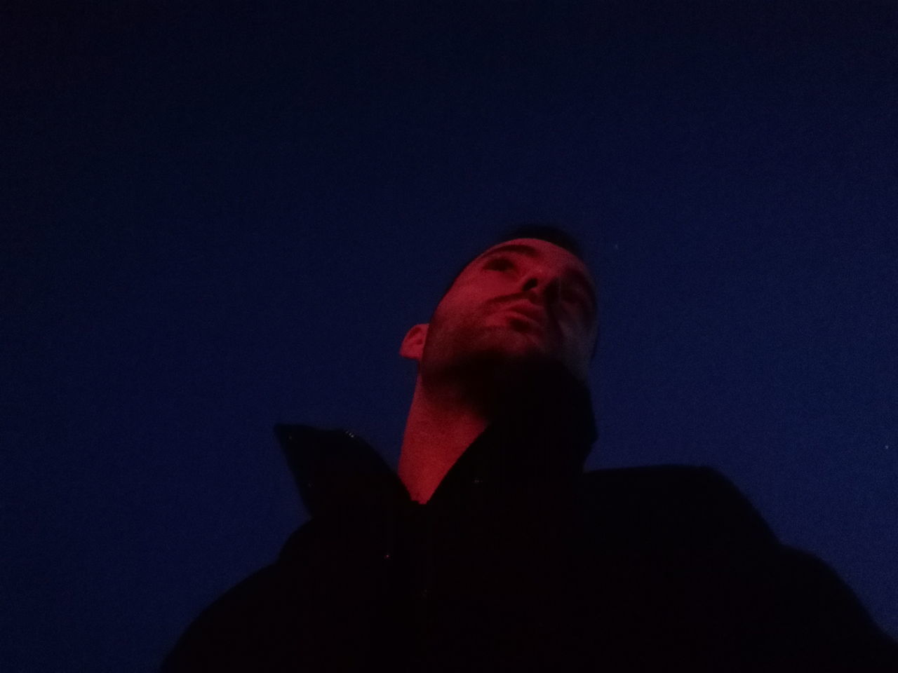 LOW ANGLE PORTRAIT OF MAN AGAINST BLUE SKY AT NIGHT