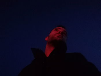 Low angle portrait of man against sky at night