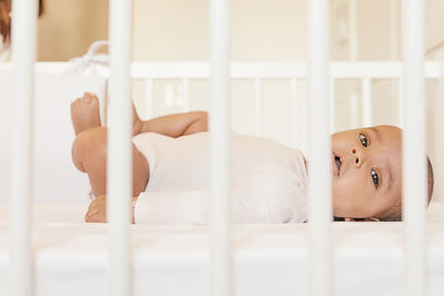 Side view of baby girl lying in crib at home