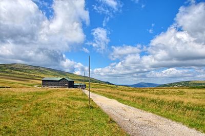 Scenic view of grassy field against cloudy sky