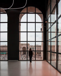 Woman looking at piazza del duomo through glass window