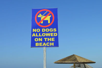 Close-up of warning sign against clear blue sky