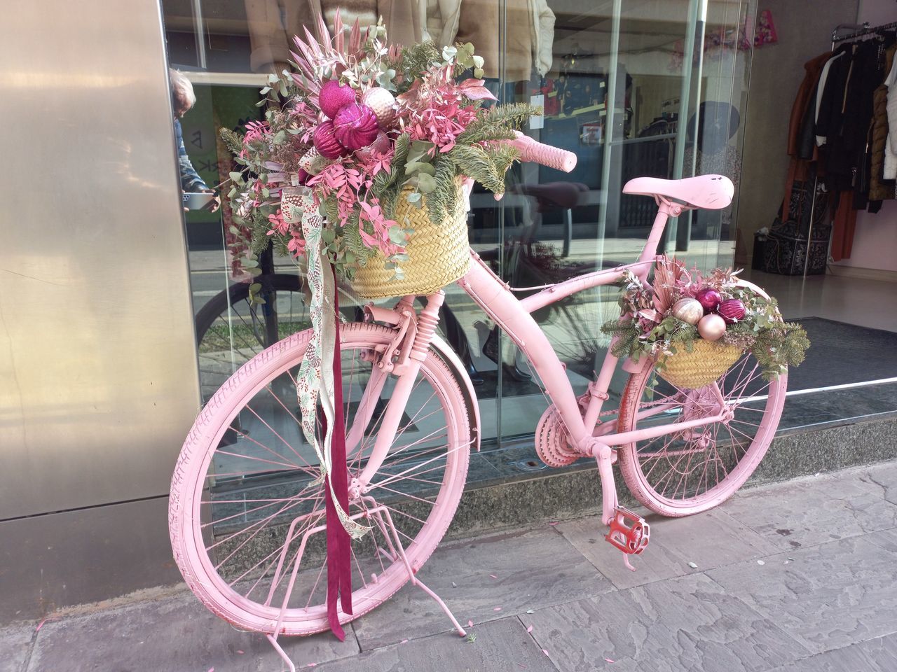 bicycle, transportation, pink, flower, flowering plant, vehicle, mode of transportation, land vehicle, plant, city, architecture, no people, nature, street, basket, building exterior, wheel, sports equipment, day, outdoors, bicycle basket, built structure, road bicycle, bouquet, flower arrangement, window, footpath, sidewalk