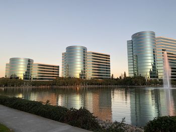 Reflection of buildings in lake against clear sky