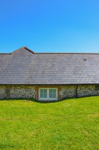 House on field against clear blue sky