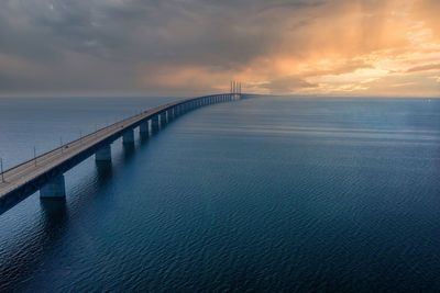 Bridge over sea against sky during sunset