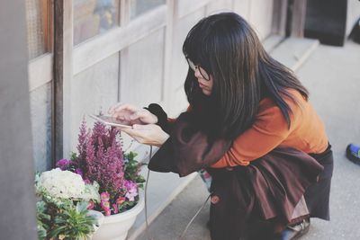 Side view of woman standing by flowering plants