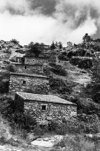 Old abandoned building by mountain against sky