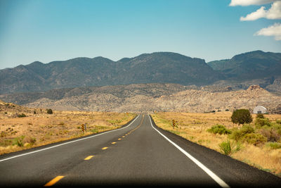 Road leading towards mountains against sky