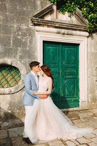 Bridegroom embracing while standing by door outdoors