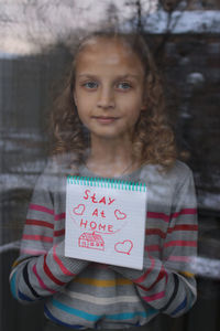 Portrait of young woman standing against wall