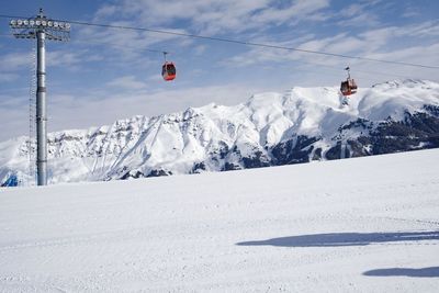 Overhead cable car on snowcapped mountains against sky