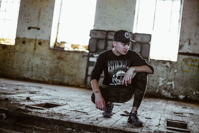 Full length of young man sitting against wall